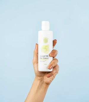 a hand holding the bottle of coconut mil hair cleanser 