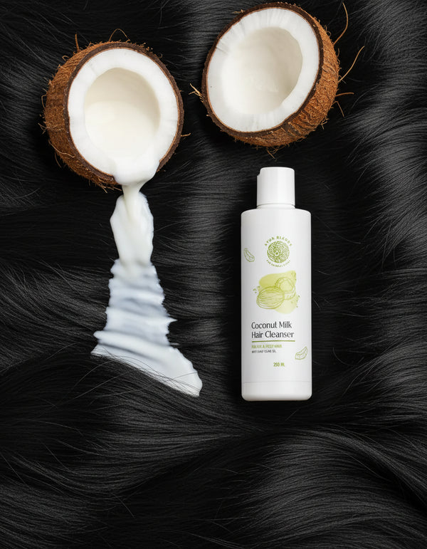 a bottle of coconut milk hair cleaner and a 2 coconuts displayed on black hair 