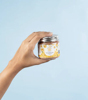 a hand holding a jar of clean up face mask