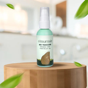 O'mumsie No Tension muscle and bone care oil for growing kids displayed on wooden table in home setting
