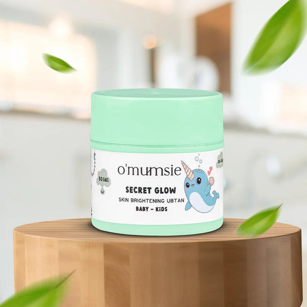 O'mumsie Secret Glow Skin Brightening Ubtan jar displayed on wooden podium, 50gms, for baby and kids