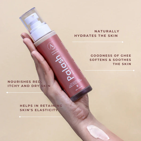 Hand holding Adhyay Palash Ghee Body Emollient with cream applied on forearm, listing benefits: naturally hydrates skin, goodness of ghee softens and soothes, nourishes red itchy dry skin, retains skin's elasticity