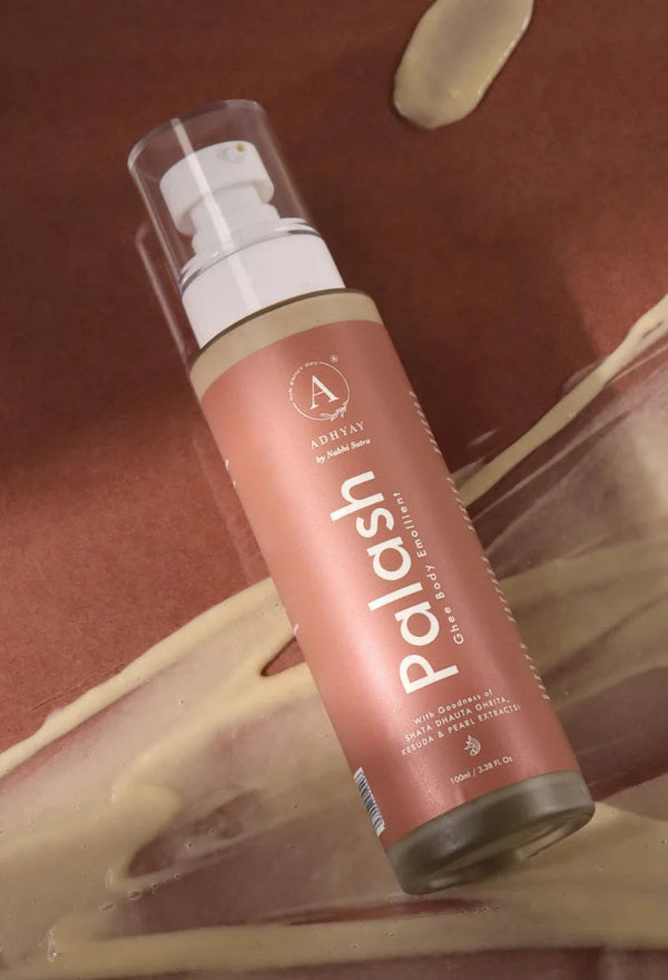Palash Ghee Body Emollient bottle lying on textured surface with cream smears, made with Shata Dhauta Ghrita and Kesuda