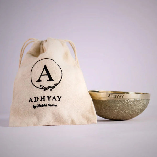Adhyay Kansa Vatki bronze bowl next to its cotton drawstring storage pouch printed with the Adhyay by Nabhi Sutra log