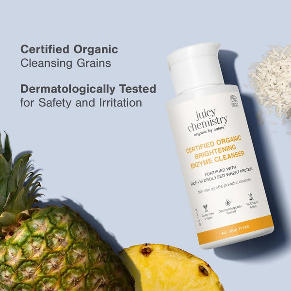 Juicy Chemistry Certified Organic Brightening Enzyme Cleanser bottle with fresh pineapple and rice grains, labeled Certified Organic Cleansing Grains and Dermatologically Tested for Safety and Irritation